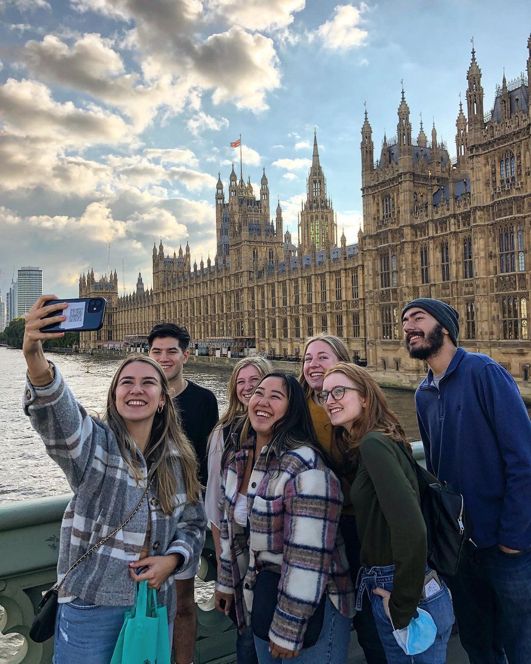 A group of people taking a selfie in front of the Palace of Westminster in London, England.
