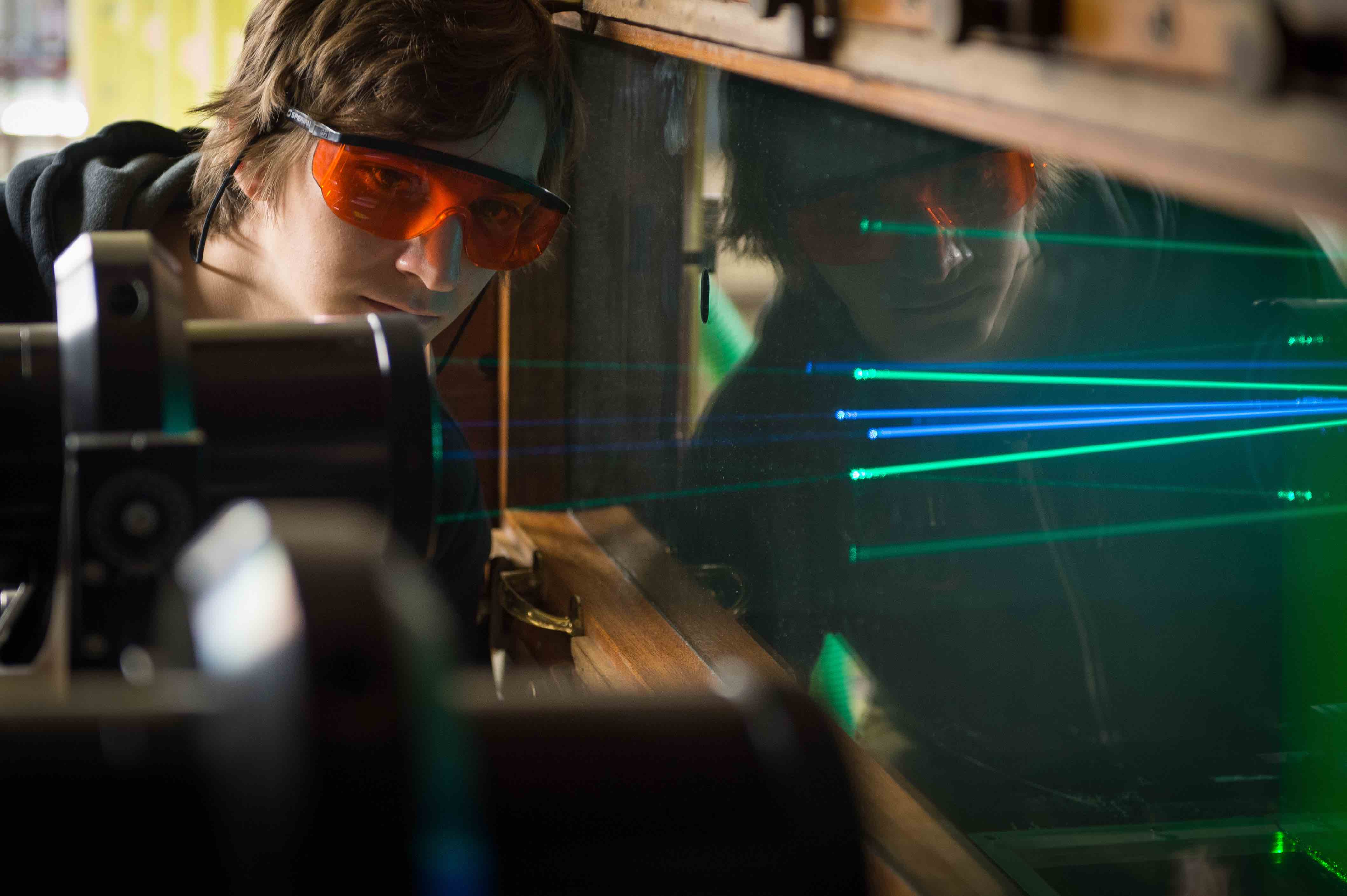 A student wearing orange glasses looking at lazers in the University of Bristol lab in Bristol, England. Photo credit: University of Bristol