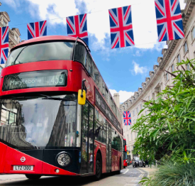 A classic double decker bus with British flags over Regent Street in London, England.