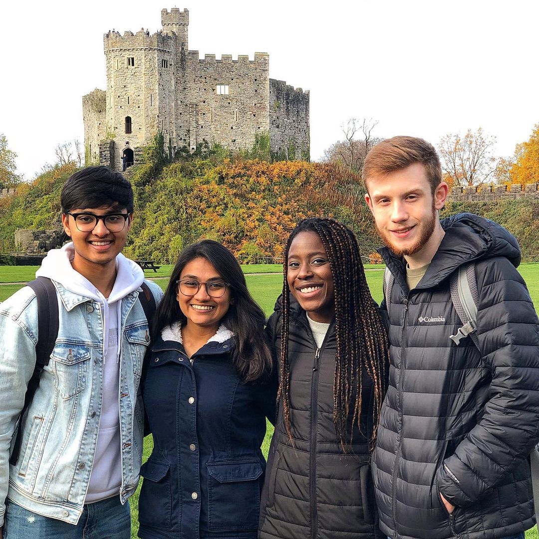 Four people posing in front of Cardiff Castle in Wales.