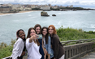 Students taking a selfie with a view of the sea in the background in Biarritz, France.