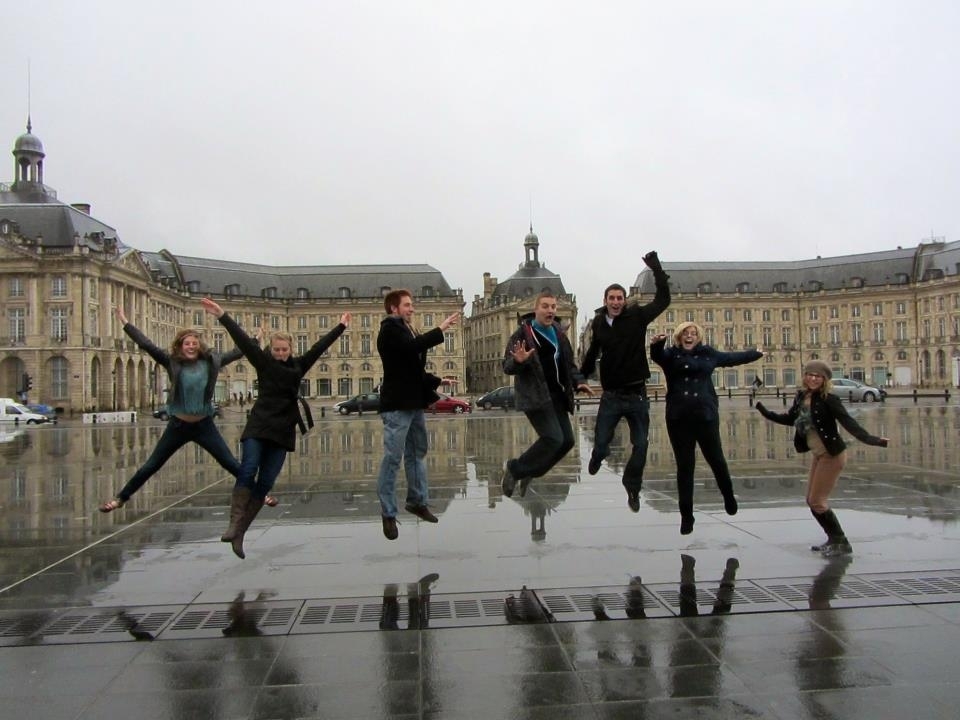 A group of students jumping in front of historic building in Bordeaux, France.