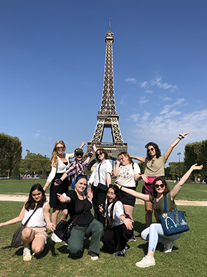 A group of students posing on the lawn in front of the Eiffel Tower in Paris, France.