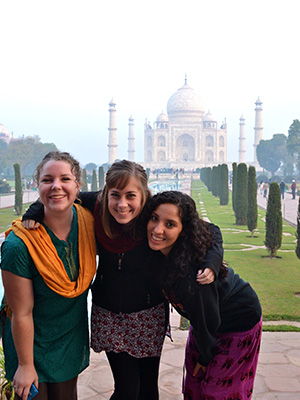 Three women standing in front of the Taj Mahal in India.