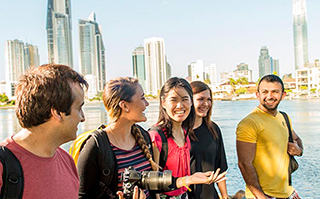 Five people walking along the Gold Coast in Australia with the city in the background.