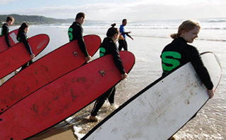 Surfers holding their surfboards getting ready to go out into the ocean in Melbourne, Australia.