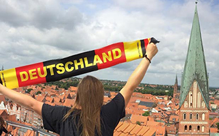 A person holding a banner that reads "Deutschland" with the city in the background in Luneburg, Germany.