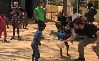 People playing soccer with children outside in Bengaluru, India.