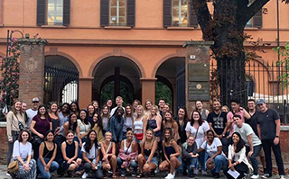 A large group of people posing in front of a building in Reggio Emilia, Italy.