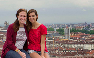 Two people sitting with a view of Torino, Italy in the background.