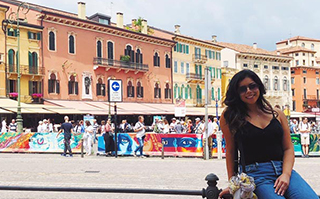 A person sitting with a view of a city market in the background in Verona, Italy.