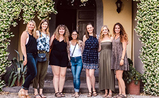 A group of people posing together outside in front of the entrance of a building in Viterbo, Italy.