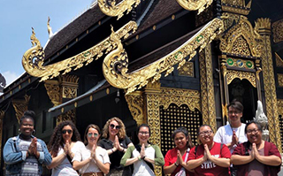 A group of people standing in front of a Wat in Chiang Mai, Thailand.