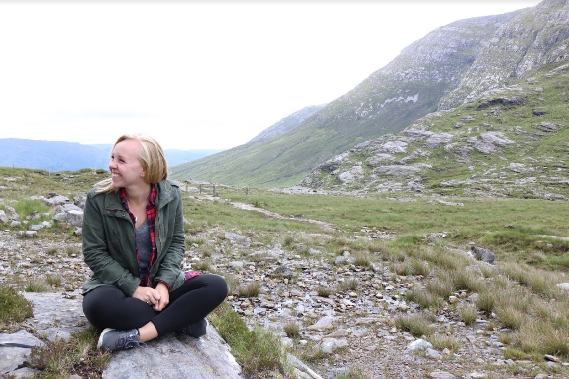 A woman sitting on a rock enjoying the views of Connemara, Ireland.