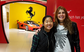 Two people posing in front of a Ferrari at the Ferrari Museum in Italy.