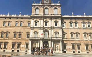 A group of students posing in front of a historic building in Modena, Italy.