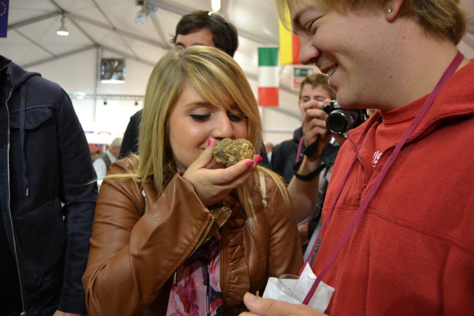 A woman smelling a truffle at the Alba Wine and Truffle Fair in Italy.