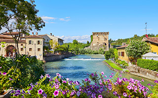 A view of the river and historic buildings in Borghetto, Italy.