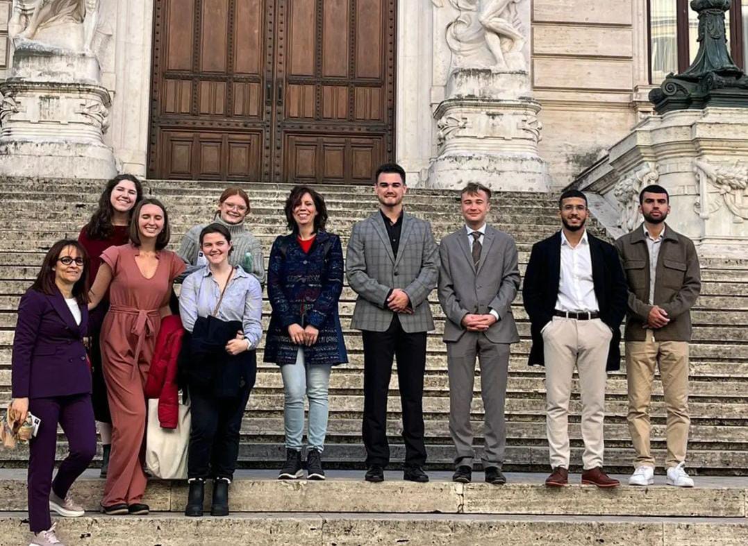A group of students standing on the steps of the Italian Parliament in Italy.