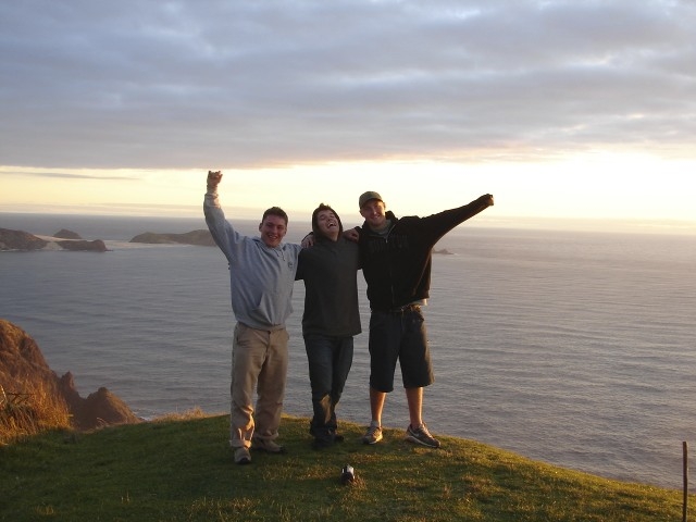 Students standing on a scenic overlook with a view of the ocean in New Zealand.