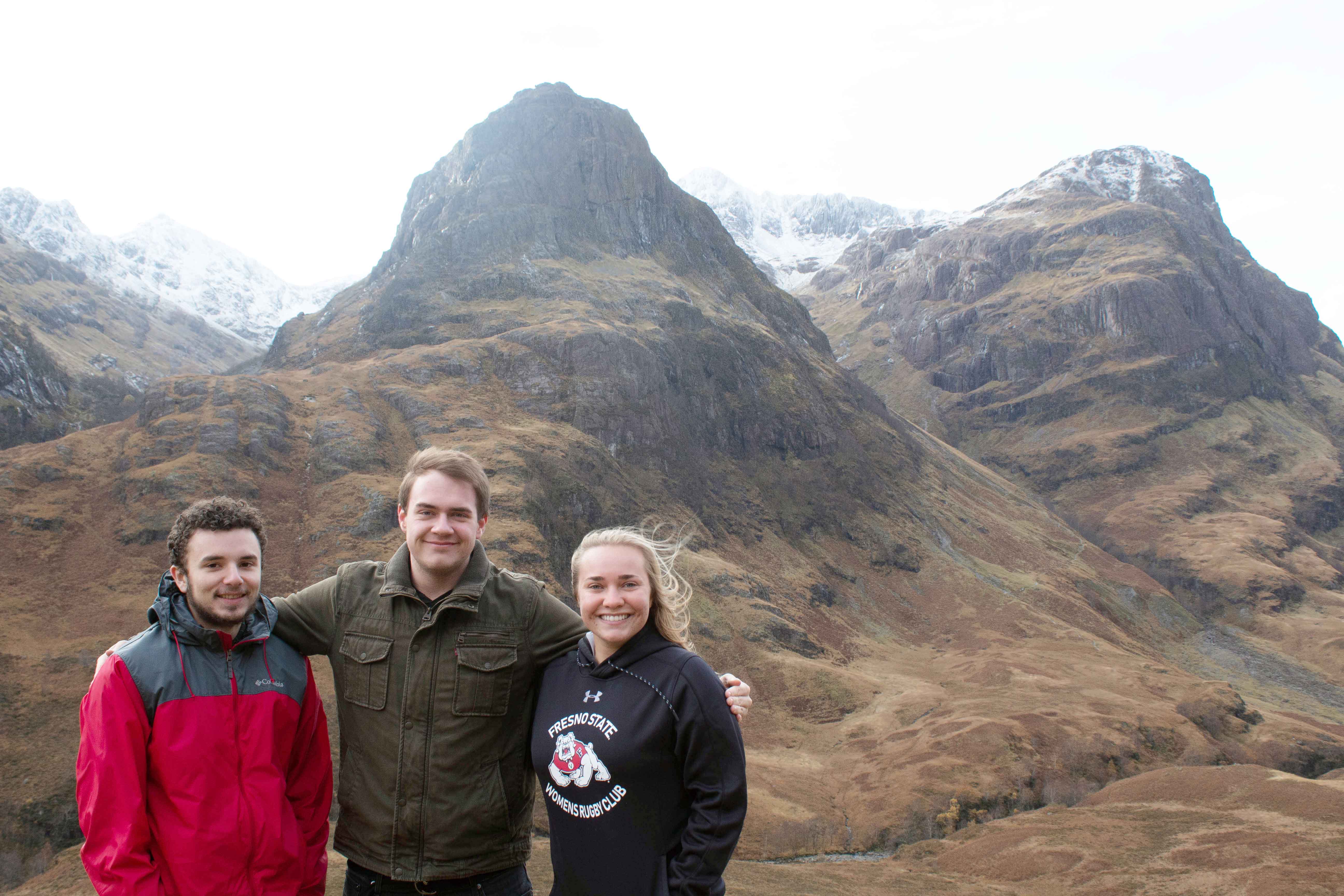 Three students with a view of the mountains behind them in Highlands, Scotland.