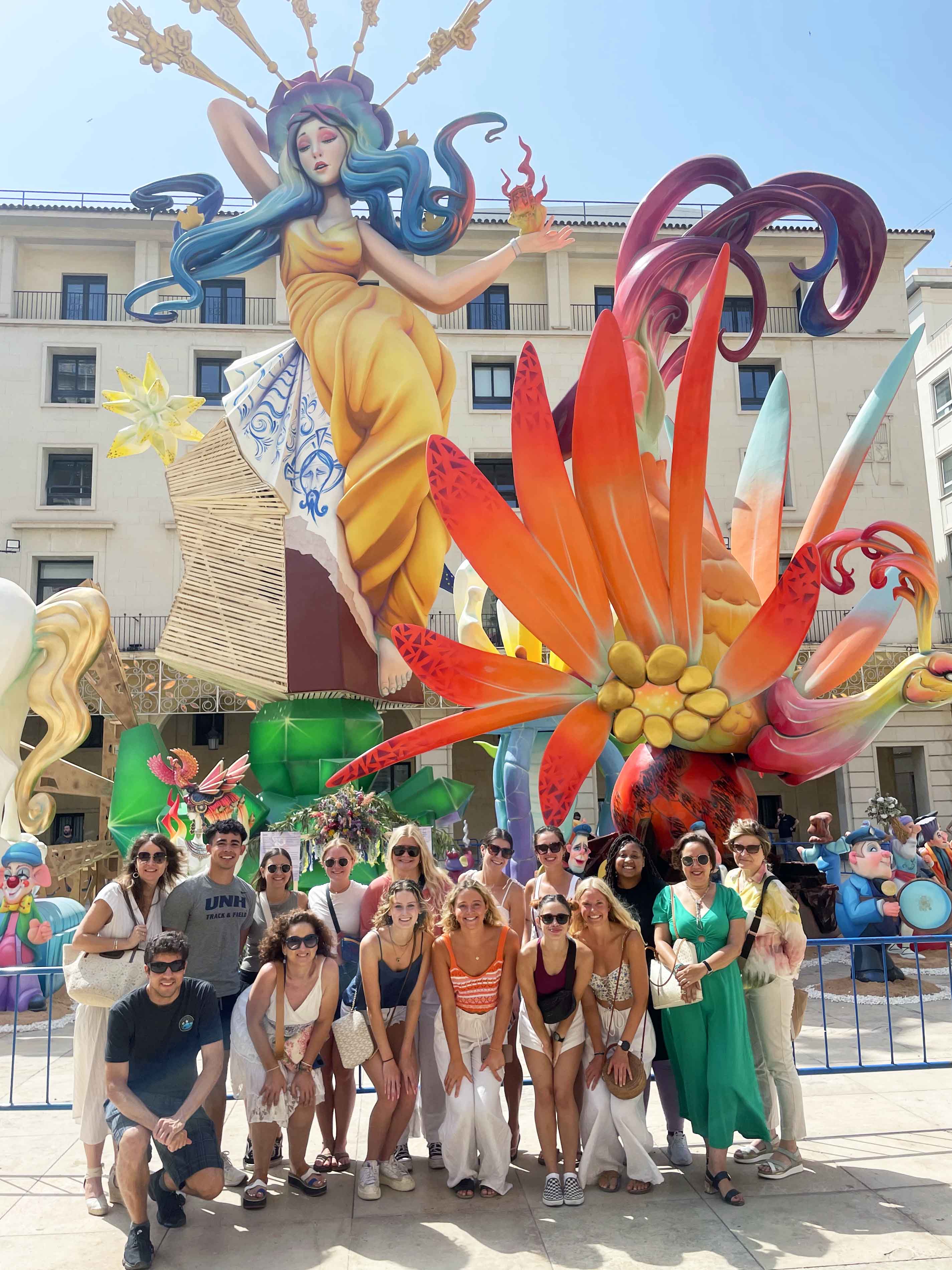 Students at a festival posing in front of a colorful sculpture in Alicante, Spain.