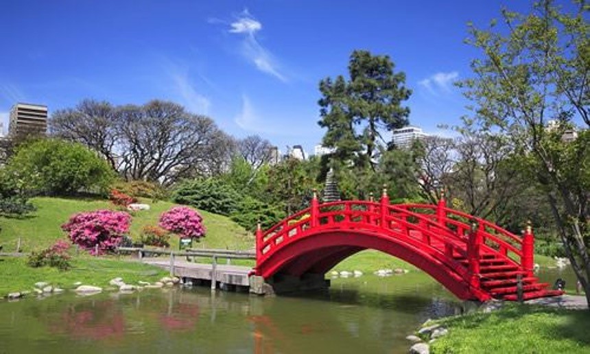 View of a garden with a red bridge in Palermo, Argentina.