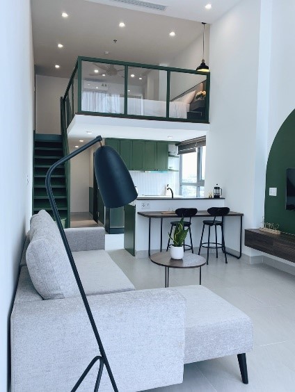 View of the kitchen, living room, and staircase leading up to a loft area in the student apartments in Da Nang, Vietnam.