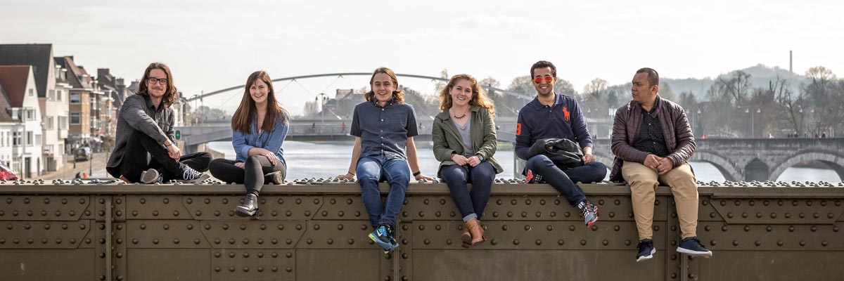 Group of students sitting on the wall of a bridge.