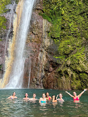 A group of students swimming next to a waterfall in Costa Rica.