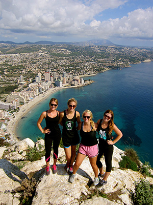 Students standing at the top of a cliff overlooking the city and sea in Spain.